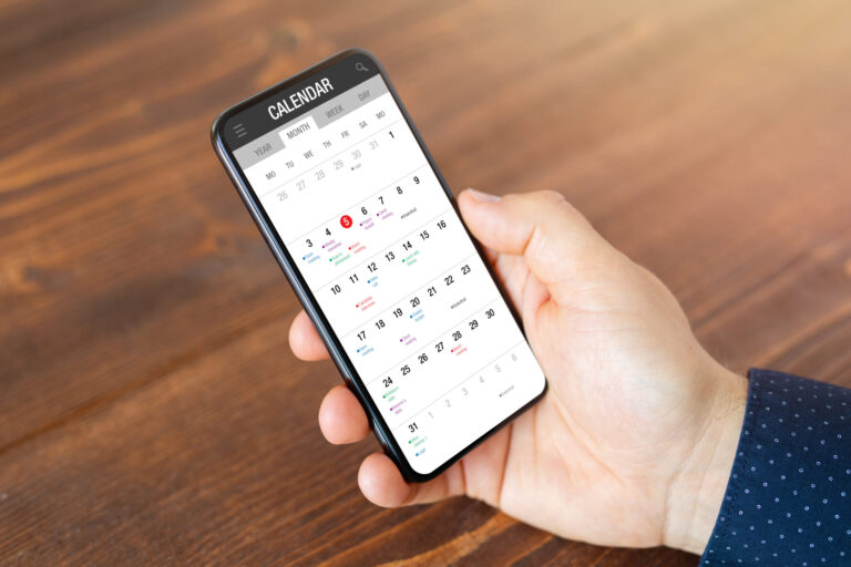 Man holding smartphone with calendar app open, illustrating strategies for using a calendar effectively with ADHD.