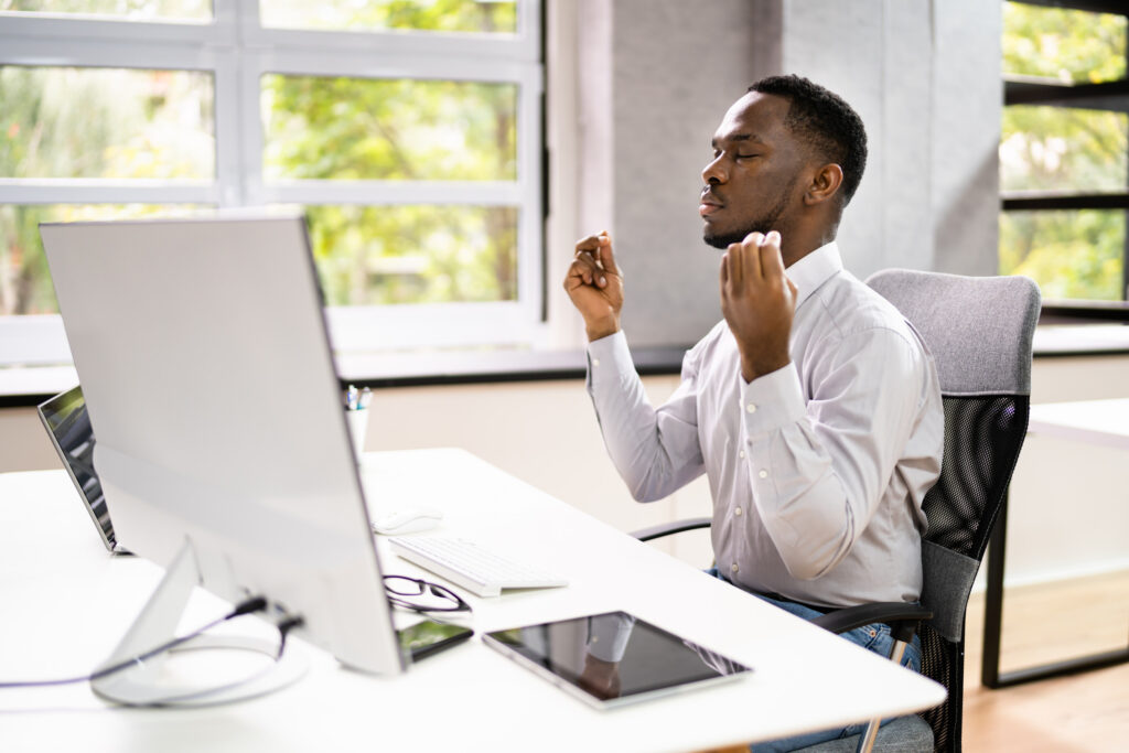 Man meditating at a computer to manage ADHD emotional dysregulation and stay calm and focused at work