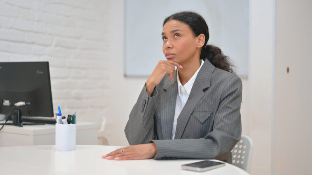 Professional woman at a desk, thoughtful, newly diagnosed adult with ADHD considering next steps.