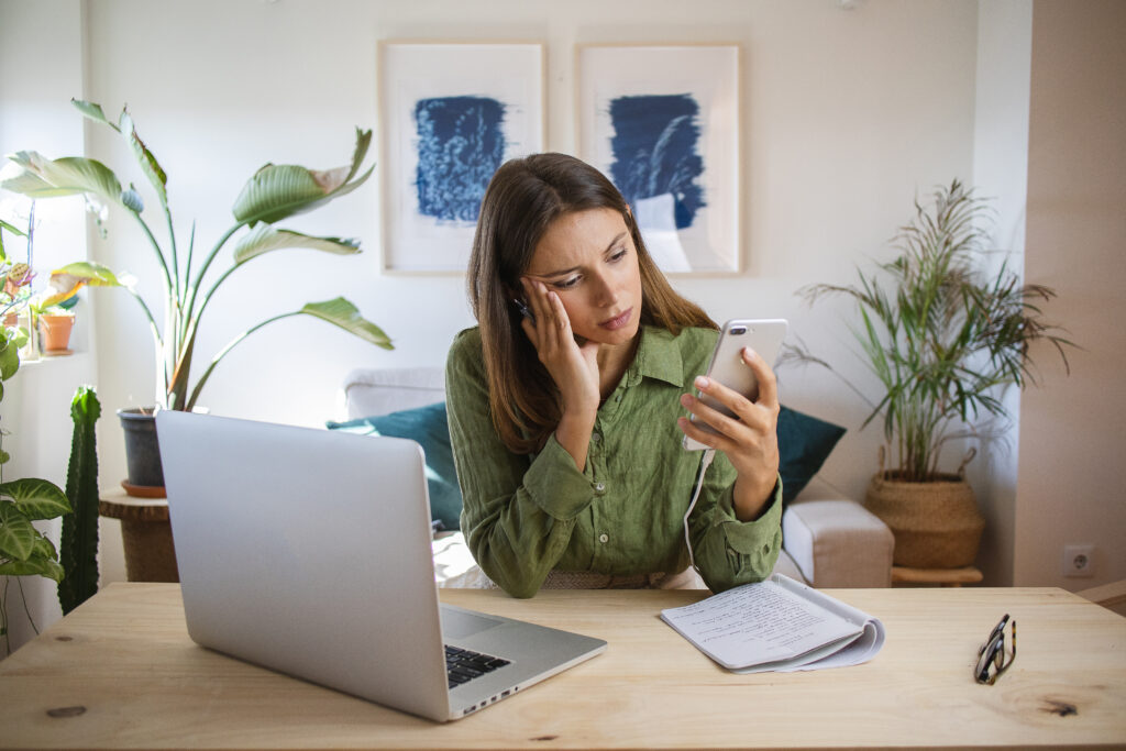 Adult woman struggling with ADHD motivation, unable to start work and distracted by her phone