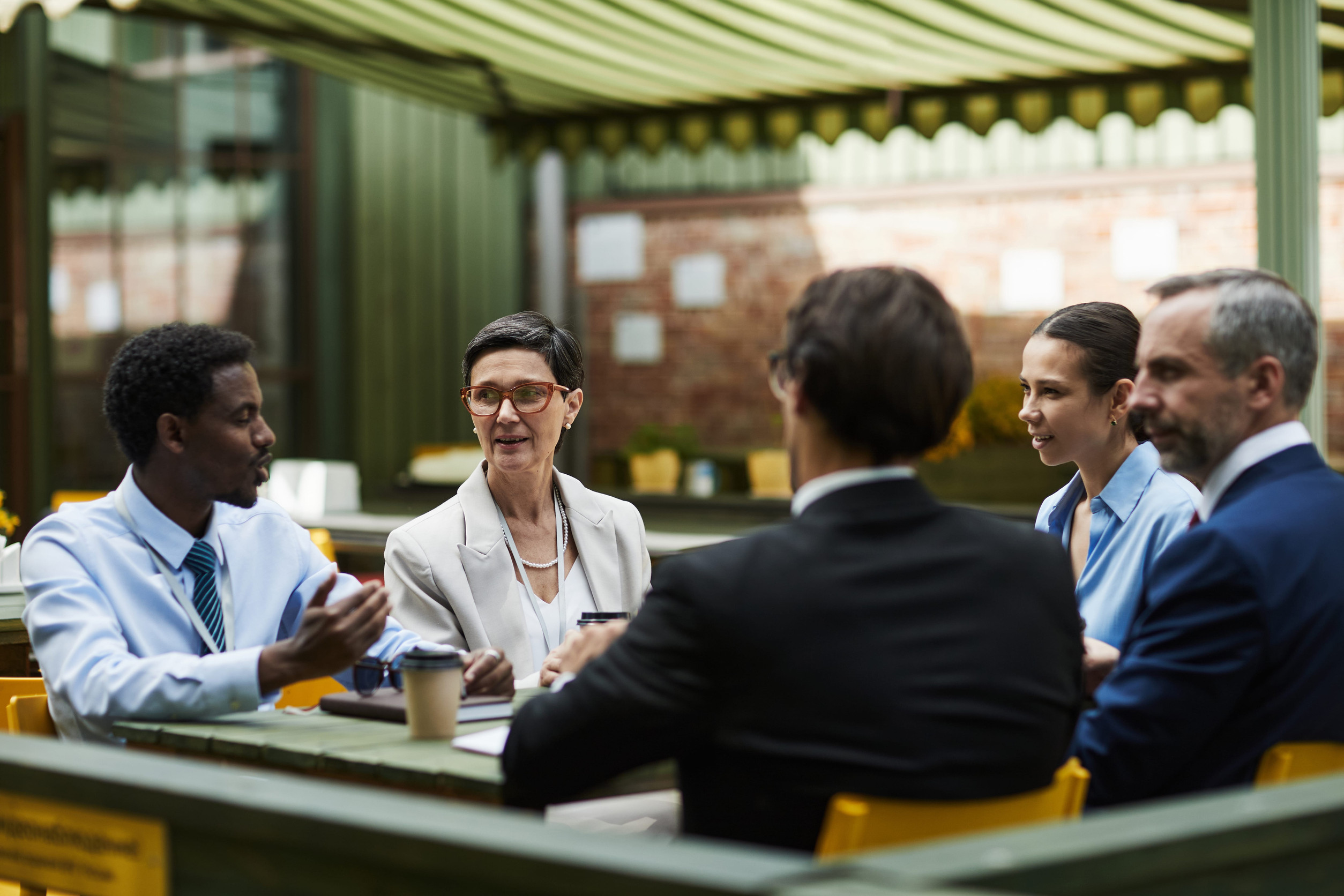 Professionals engaged in a group conversation during a meeting, representing ADHD and slow processing speed in real-time conversations.