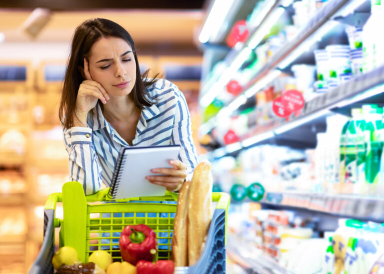 Woman with ADHD grocery shopping while checking a meal planning list, illustrating the everyday challenges of home management and decision-making for adults with ADHD.